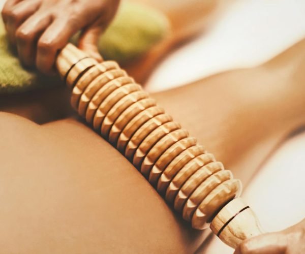 Unrecognizable woman having a anti cellulite wood therapy at beauty spa.